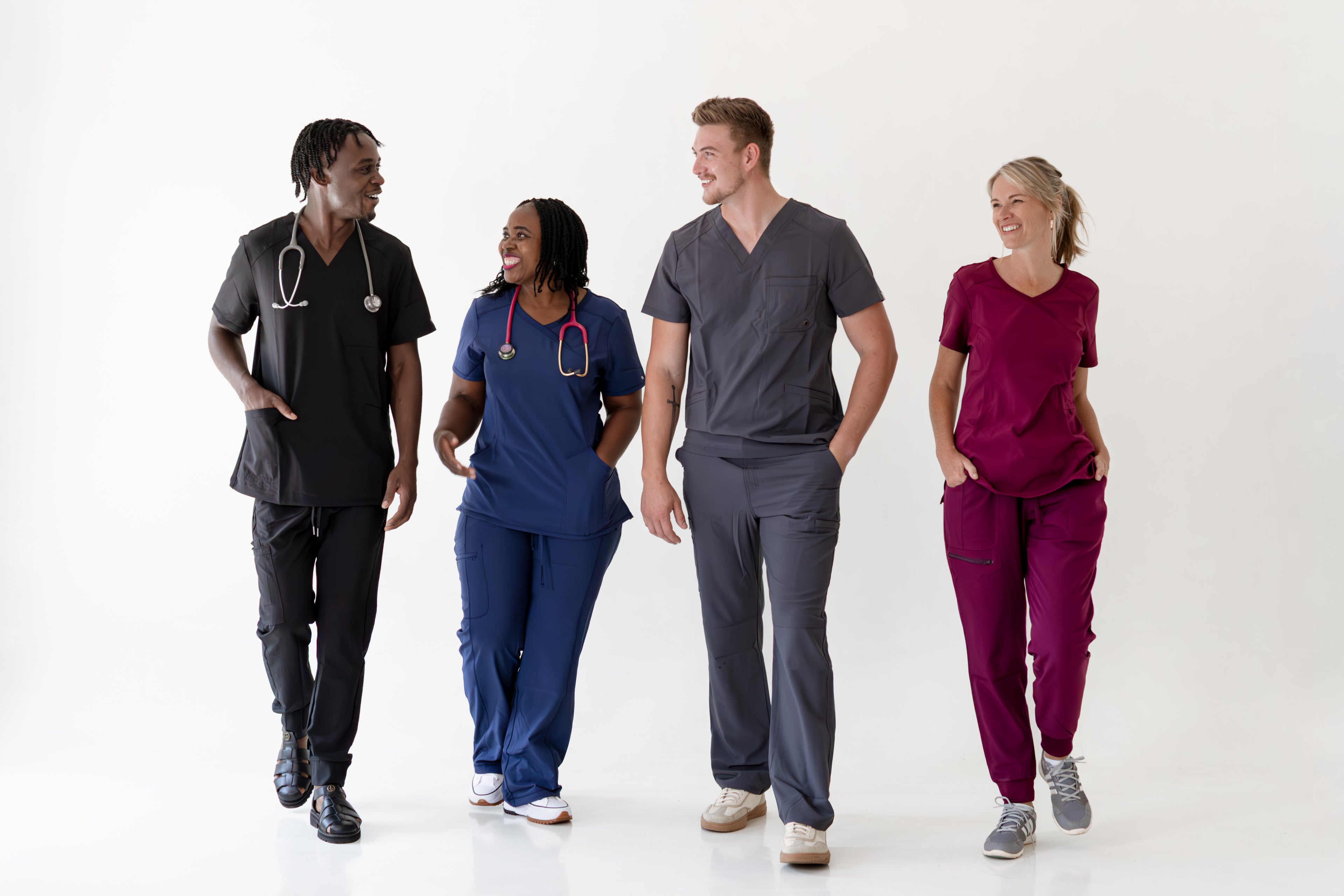 Four individuals in medical scrubs walking on a white background