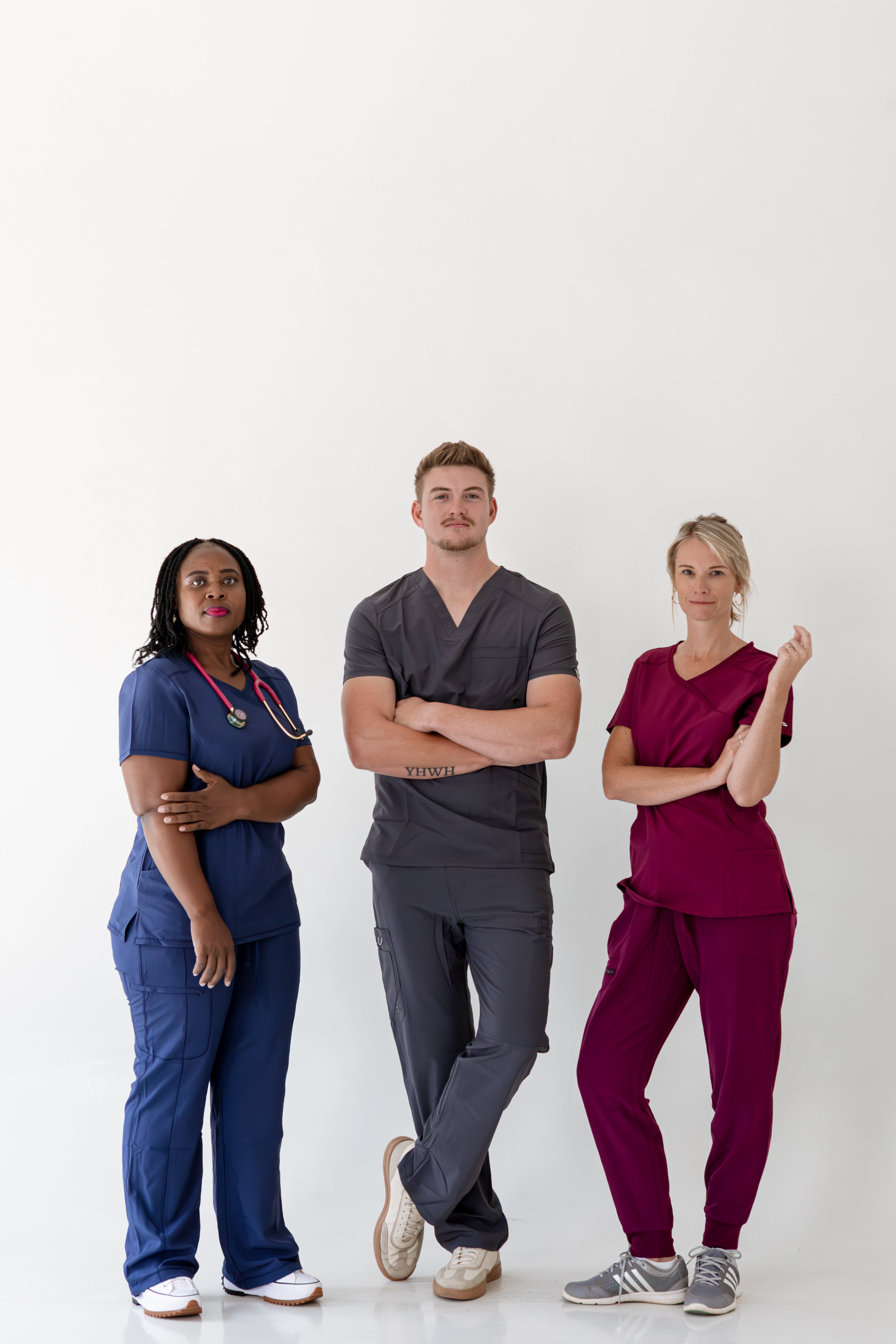 Three healthcare professionals in colorful scrubs standing against a white background